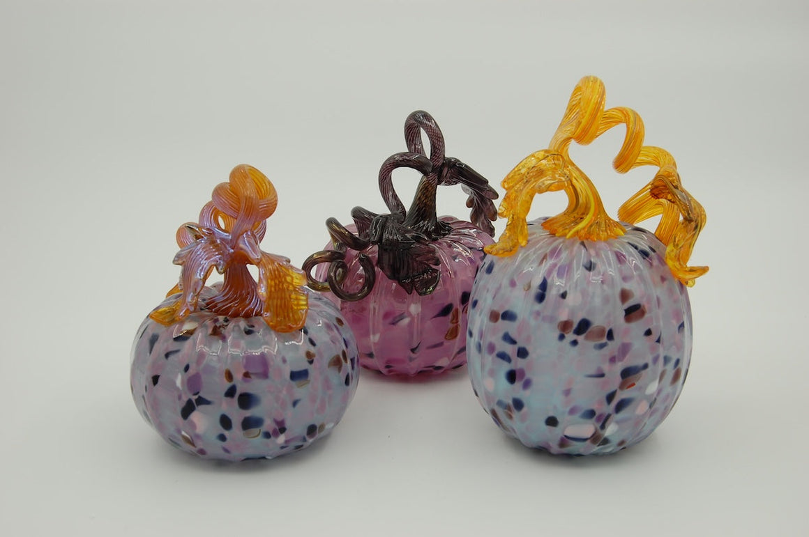 A trio of glass pumpkins in shades of lavender and gold