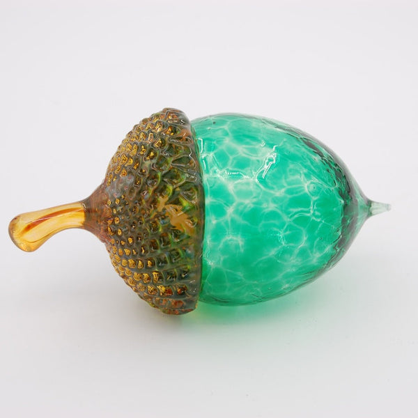 Decorative glass acorn with green cap and brown base on a white background