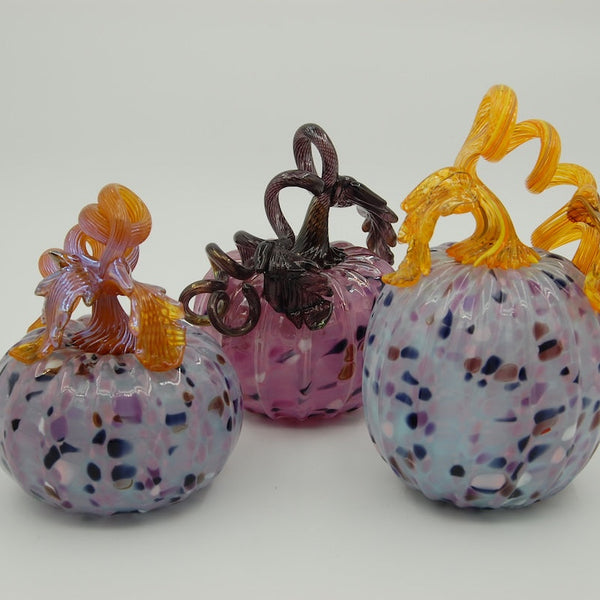 Three colorful glass pumpkins with decorative elements on a white background