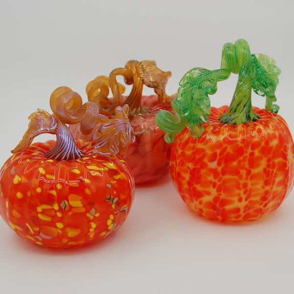Three glass pumpkins with colorful designs on a white background