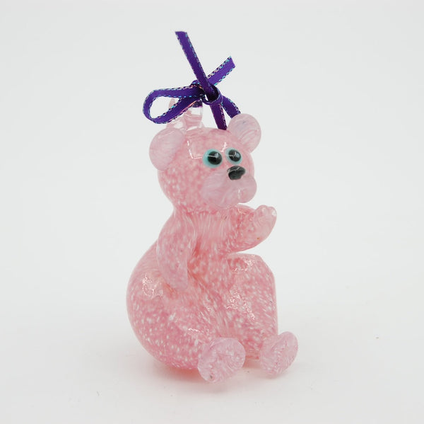 pink blown glass teddy bear ornament with a purple bow on a white background
