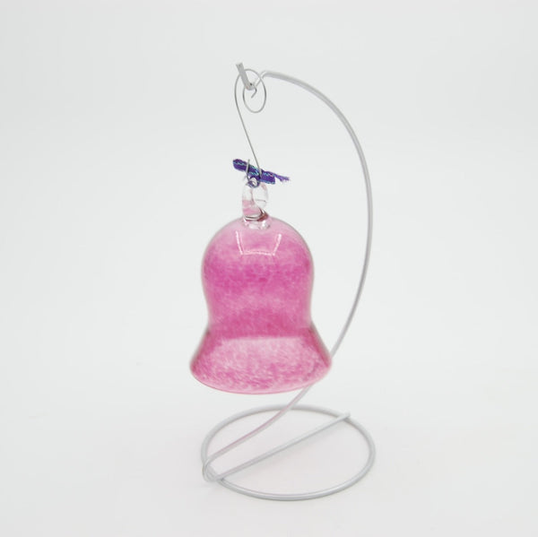 Pink glass bell with a metal stand on a white background