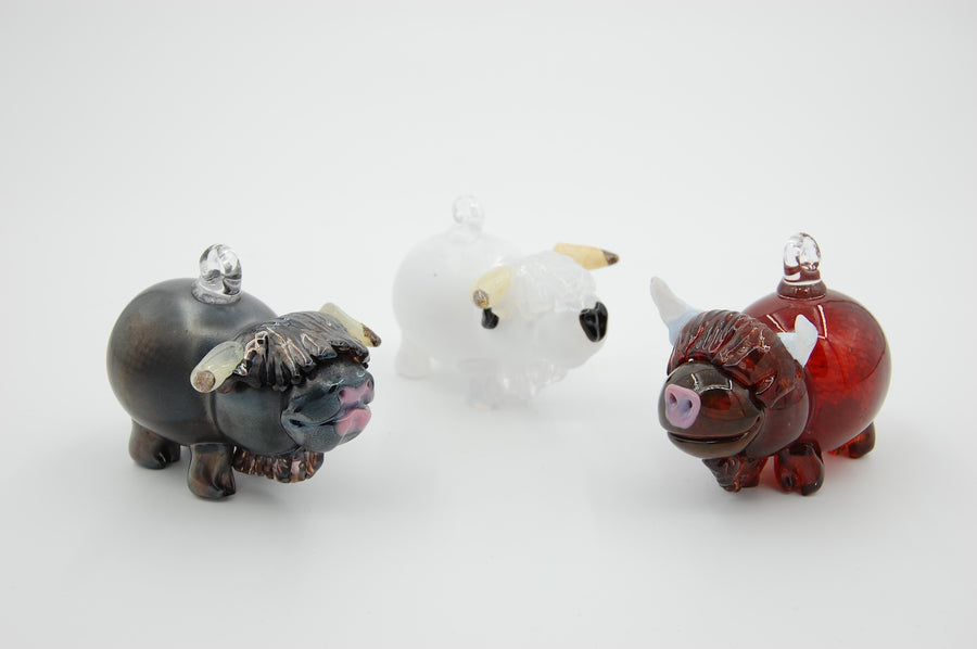hand blown glass highland cow ornaments on a white background