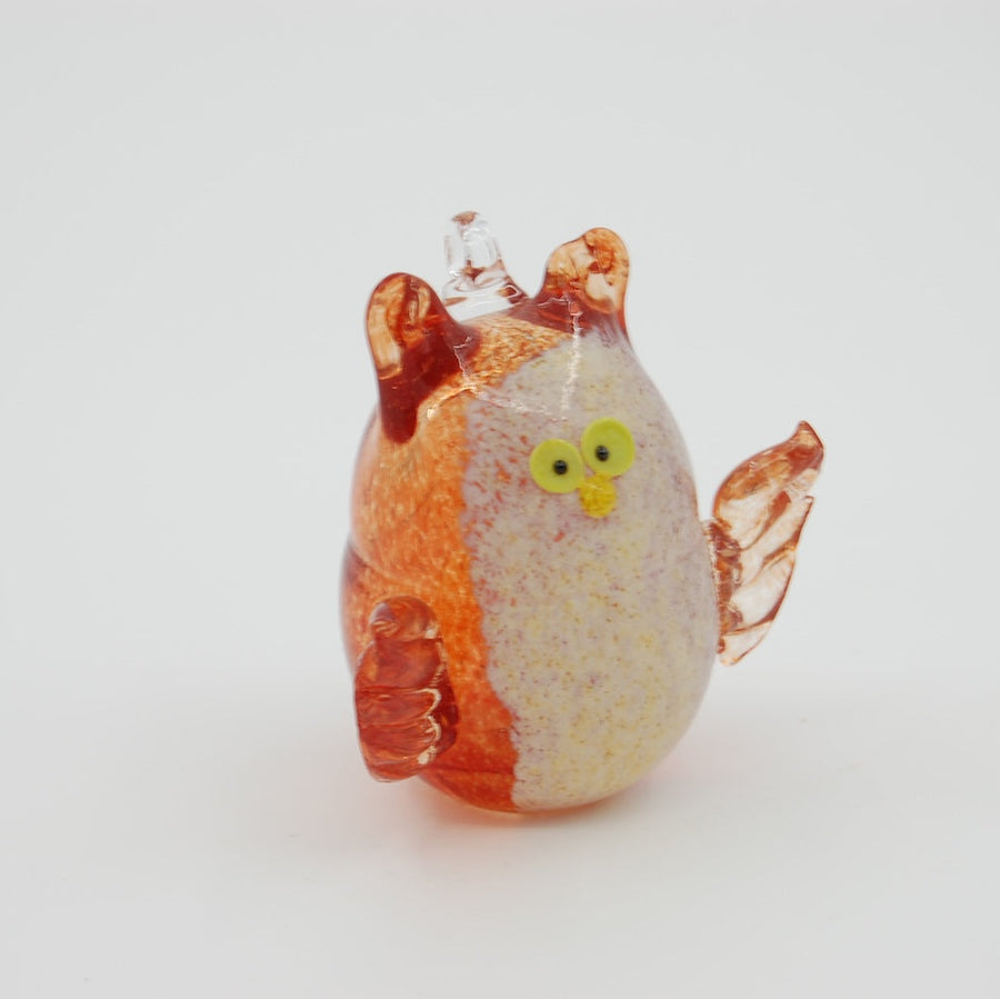 Glass figurine of an owl white belly and orange wings on a white background