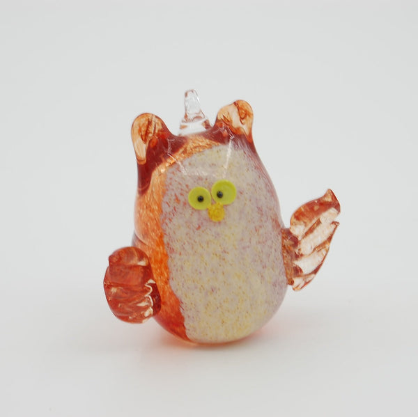 Glass figurine of an owl white belly and orange wings on a white background